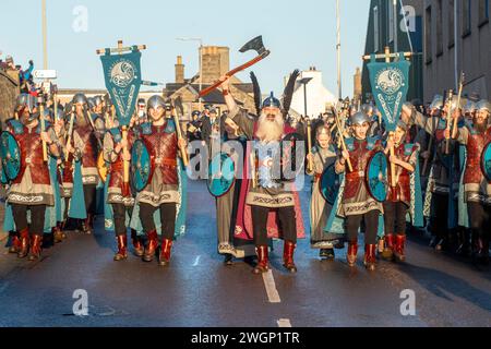 Les membres de la Jarl Squad 2024 défilent à travers Lerwick sur les îles Shetland pendant le festival Up Helly AA. Les filles de première année étaient dans Jarl Squad. Banque D'Images