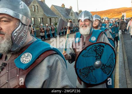 Les membres de la Jarl Squad 2024 défilent à travers Lerwick sur les îles Shetland pendant le festival Up Helly AA. Les filles de première année étaient dans Jarl Squad. Banque D'Images