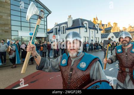 Les membres de la Jarl Squad 2024 défilent à travers Lerwick sur les îles Shetland pendant le festival Up Helly AA. Les filles de première année étaient dans Jarl Squad. Banque D'Images