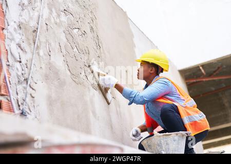 Travail féminin jeune plâtrage sur mur avec ciment Banque D'Images