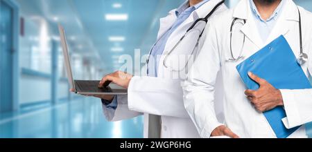 Une paire de professionnels de la santé dans un couloir hospitalier, l'un utilisant un ordinateur portable Banque D'Images
