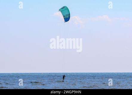 Gilgo Beach, New York, États-Unis - 13 août 2023 : un homme qui tient sur un grand kitesurf couleur aqua dans l'océan Atlantique au large de la côte de Gilgo B. Banque D'Images