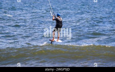 Veiw arrière d'un homme montant sur une planche tenant un cerf-volant pendant le kitesurf dans l'océan Atlantique. Banque D'Images