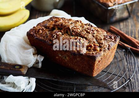 Vue aérienne du pain de banane frais maison refroidi sur une grille de boulanger avec des ingrédients à proximité. Mise au point sélective sur pain avec arrière-plan flou Banque D'Images