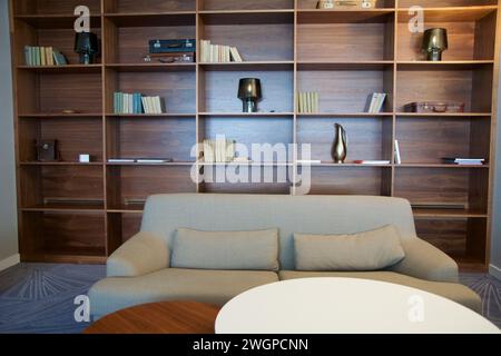 BRESLAU, POLOGNE - 15 juin 2018 : canapé de couleur claire devant une étagère avec divers objets décoratifs dans le salon exécutif d'un hôtel de luxe Banque D'Images