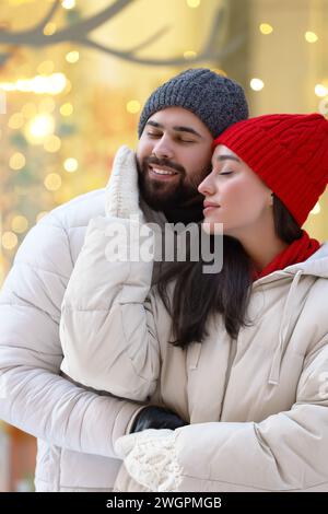 Portrait de couple charmant à l'extérieur contre des lumières floues à l'extérieur Banque D'Images