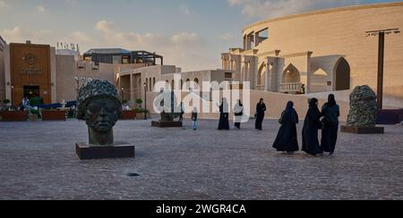 Katara Village culturel à Doha, Qatar vue du coucher du soleil montrant les trois singes et restaurants de Gandhi avec des visiteurs marchant et assis Banque D'Images
