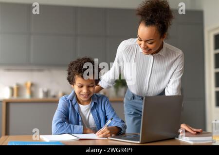 Mère aide son fils avec les devoirs sur ordinateur portable à la maison Banque D'Images