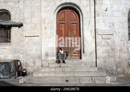 Un homme est assis à l'entrée de l'Hospice autrichien de la Sainte famille à Jérusalem, Israël Banque D'Images