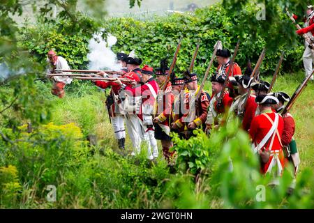 Des reconstituteurs historiques jouent un combat de guerre révolutionnaire entre les Red Coats britanniques et les rebelles américains à Old Sturbridge Village à Sturbridge, au Missouri Banque D'Images