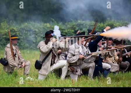 Des reconstituteurs historiques jouent un combat de guerre révolutionnaire entre les Red Coats britanniques et les rebelles américains à Old Sturbridge Village à Sturbridge, au Missouri Banque D'Images