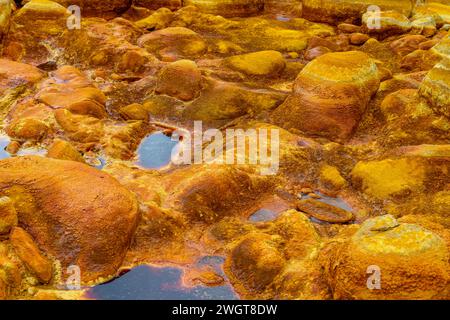 Les gisements minéraux oranges chauds de Rio Tinto sculptent un paysage texturé avec des flaques réfléchissantes Banque D'Images