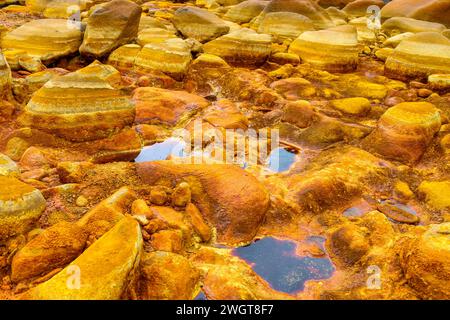 Les gisements minéraux oranges chauds de Rio Tinto sculptent un paysage texturé avec des flaques réfléchissantes Banque D'Images