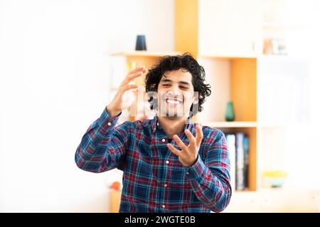 jeune homme à la maison faisant des signes avec les mains Banque D'Images