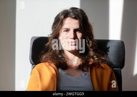 Jeune femme assise à la maison dans son bureau au soleil Banque D'Images