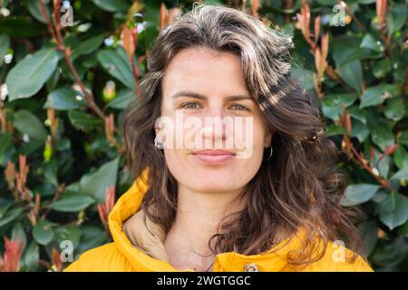 jeune femme debout dehors, souriant devant les feuilles Banque D'Images