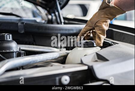 Mécanicien remplissage du liquide de refroidissement du moteur de voiture gros plan Banque D'Images