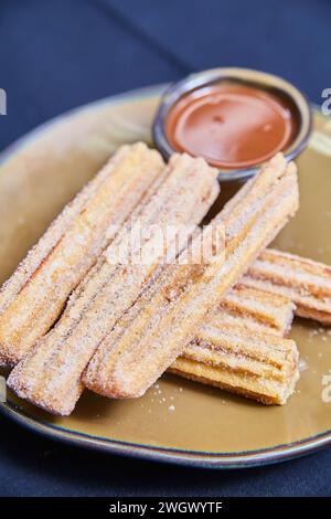 Churros enrobés de sucre croustillant avec sauce au chocolat sur assiette en céramique Banque D'Images