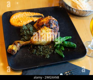 Pilon de poulet au couscous avec curry noir, poivrons et Romesco Banque D'Images