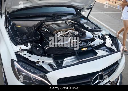 Berlin, Allemagne - 20 août 2022 : Mercedes Benz C 63 S AMG moteur gros plan avec des détails carbone et beaucoup de jambes féminines qui passent. Banque D'Images