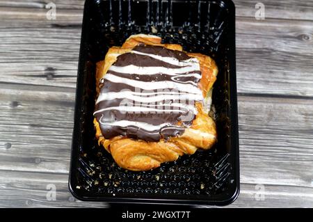 Pâtisserie danoise cuite farcie et garnie de chocolat noir brun et sauce au chocolat blanc, pâte à pâtisserie sucrée cuite au four avec de la farine, du sucre et Banque D'Images