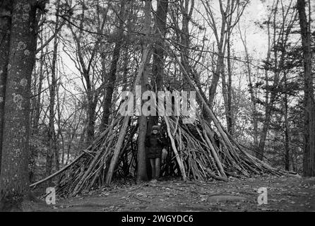 The Trustees DeCordova sculpture Park and Museum - Lincoln, ma. Une femme se tient sous une pile de branches d'arbre dans la formation d'un tipi dans une clairière. Banque D'Images