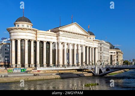 Skopje, Macédoine du Nord - 23 octobre 2023 : les gens traversent le pont de la rivière Vardar pour entrer dans le musée archéologique de Macédoine du Nord bâtiment sur Coas Banque D'Images