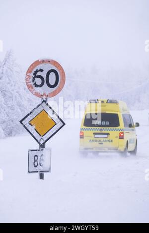 Ambulance passant une vitesse de 60 km/h et panneaux routiers prioritaires dans des conditions de conduite glacées sur une autoroute à Senja, Norvège, Scandinavie, Europe Banque D'Images