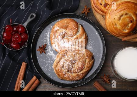 Délicieux rouleaux avec de la poudre de sucre, des baies et des épices sur la table en bois, plat. Petits pains sucrés Banque D'Images