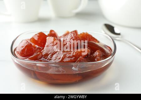 Confiture de coing dans un bol en verre sur une table blanche, gros plan Banque D'Images