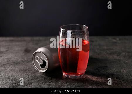 Boisson énergisante en verre et canette en aluminium sur table grise Banque D'Images