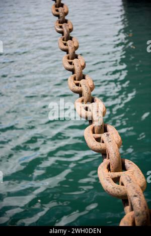 Ancre de chaîne de navire rouillé dans le fond abstrait d'eau de mer. Banque D'Images