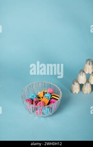 La réglisse britannique allsorts bonbons dans un bol en verre sur fond bleu clair Banque D'Images