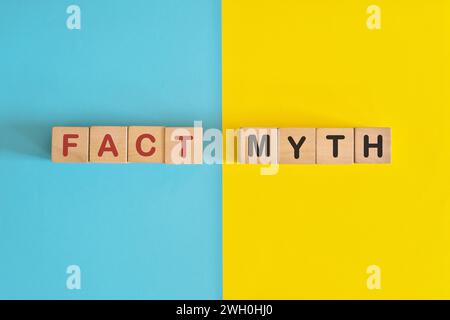 Fait versus mythe concept d'information. Typographie de blocs en bois en fond bleu vif et jaune. Banque D'Images