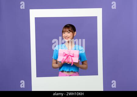 Photo de la belle femme millénaire asiatique ne blog tenir la boîte-cadeau isolée sur fond de couleur Banque D'Images