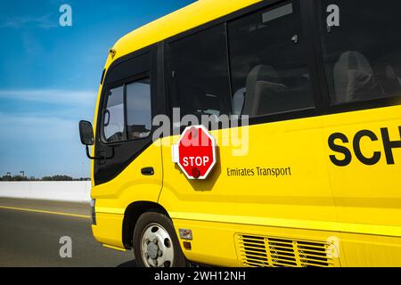 Conduite d'autobus scolaire dans la ville de Dubaï, Émirats arabes Unis. Un autobus scolaire jaune conduisant le long de la route. Photo de voyage, personne, espace de copie pour le texte Banque D'Images