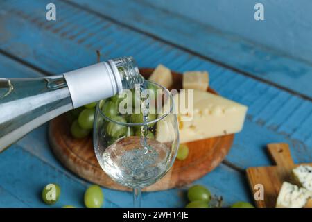 Vin blanc versant dans le verre sur fond de couleur, gros plan Banque D'Images