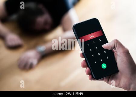 Appel d'urgence 112. Accident ou épilepsie. Jeune homme inconscient s'évanouit allongé sur le sol. Alarme d'ambulance SOS avec téléphone en main. Banque D'Images