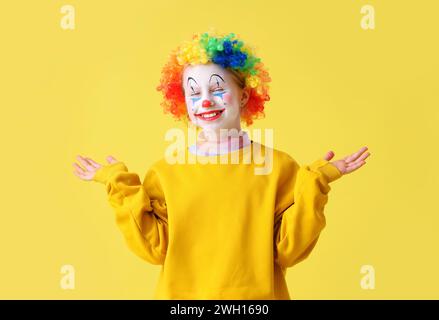 Drôle petite fille dans la perruque clown sur fond jaune. Célébration du jour des fous d'avril Banque D'Images