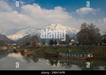 Non exclusif : février 05,2024, Srinagar Cachemire, Inde : Une vue de la rivière Jhelum et de la neige couverte des collines de Zabarwan pendant une journée ensoleillée après la neige fraîche Banque D'Images