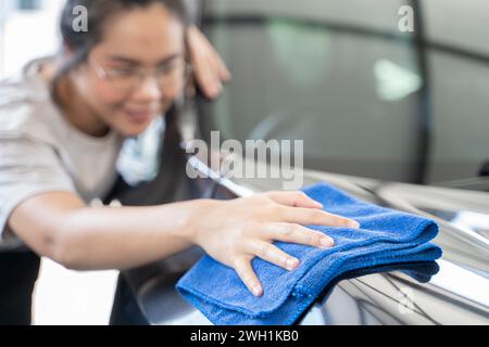 Femmes frottant la voiture avec un chiffon d'essuyage. Banque D'Images