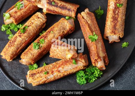 pain grillé français au jambon et au fromage au blé entier servi avec sauce tomate sur une assiette noire sur une table en béton gris, gros plan Banque D'Images