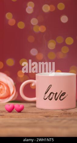 boisson chaude avec de la fumée dans une tasse de café rose écrivant le mot amour à côté, avec rose et deux petits coeurs placés côte à côte sur une table en bois, lumière bokeh Banque D'Images