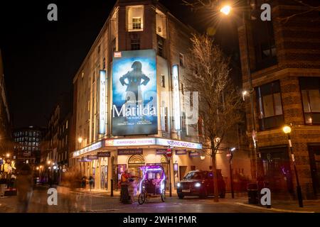 Londres. UK- 02.04.2024. Une vue extérieure nocturne du Cambridge Theatre montrant la façade, l'entrée et le panneau d'affichage de la comédie musicale Matilda. Banque D'Images