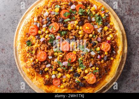 Pizza Tex Mex maison avec bœuf haché, légumes, fromage cheddar et épices mexicaines gros plan sur une planche de bois sur la table. Vue horizontale de dessus fr Banque D'Images