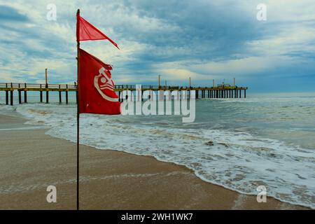 Drapeau avec interdiction de baignade se développe dans le vent, plage de la côte Atlantique, Villa Gesell, Argentine, 02.01.2024 Banque D'Images