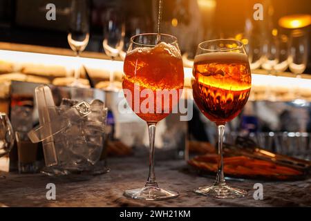 Deux verres de cocktail Aperol spritz sur le comptoir du bar. Préparation de boissons alcoolisées italiennes typiques, apéritif à base de vin blanc mousseux Prosecco, glace Banque D'Images