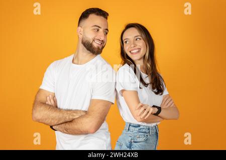 Un jeune couple satisfait se tient les bras croisés, souriant l'un à l'autre Banque D'Images