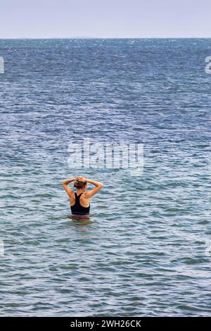 Une femme est dans l'eau regardant vers la mer sur la plage d'Amager à Copenhague Banque D'Images
