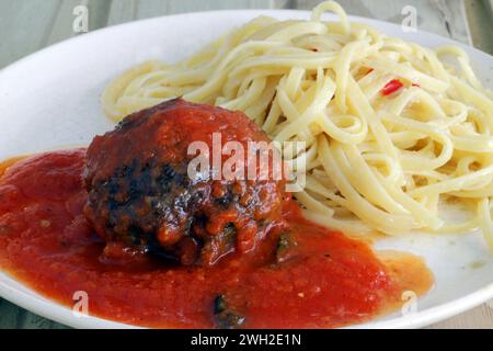 Délicieuse polpétone dans une riche sauce sugo servie avec des spaghettis dans de l'ail parfumé et de l'huile Banque D'Images